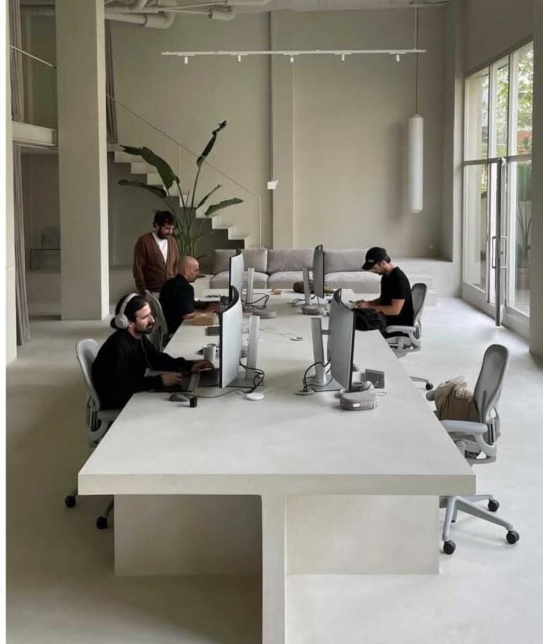 Long communal microcement workstation table in modern Dubai creative studio